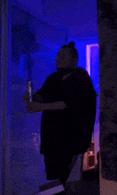 a man in a black shirt is holding a light saber in a dark room