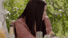 a woman with long black hair is sitting at a table with a glass of champagne and a bottle of champagne .