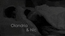 a black and white photo of a couple laying in bed with the words olandria & nic