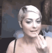 a woman is applying lip gloss to her lips while looking at herself in the mirror .