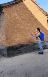 a woman is spraying a brick wall with a long stick
