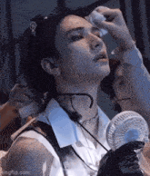 a woman is holding a fan and wiping her face with a towel .