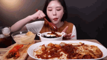 a woman is eating a plate of food with a spoon in her mouth
