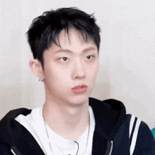 a close up of a young man making a funny face while wearing a hoodie .
