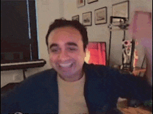 a man is smiling and holding a microphone in a room with pictures on the wall