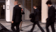 a group of people are walking in front of a building with a sign that says no smoking on it
