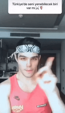 a man wearing a bandana and a red nike tank top giving a peace sign