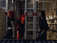 two women are walking in a warehouse with a red sign that says 5205
