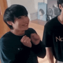 a couple of young men are standing next to each other in a room and one of them is smiling .