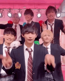 a group of young men in suits and ties are standing next to each other on a pink stage .