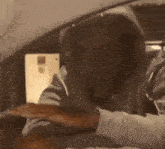 a man in a hoodie is sitting in a car with his hands on the steering wheel .