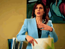a woman in a blue jacket is holding a folder with a sticker that says ' a ' on it