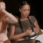 a woman is sitting next to another woman on a bed and holding her hand .