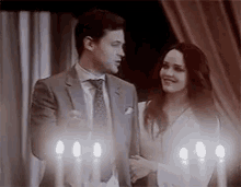 a man and woman are standing next to each other in front of candles