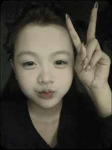 a young girl giving a peace sign with her finger