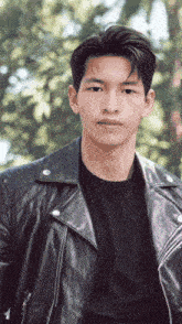 a young man wearing a black shirt and a leather jacket