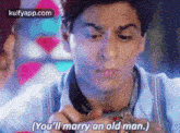 a man is holding a ring in his hand and saying `` you 'll marry an old man '' .