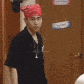 a man wearing a bandana stands in front of a door that has a vacant sign hanging on it