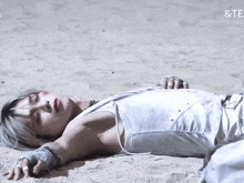 a person laying on a sandy beach with the word te on the bottom right