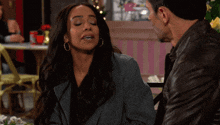 a man and a woman are sitting at a table and the woman has her eyes closed