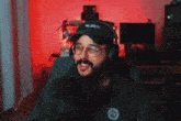a man wearing headphones and a hat is sitting in front of a microphone and smiling