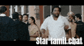 a man in a white shirt is standing in front of a crowd of people with the words star tamil chat written below him