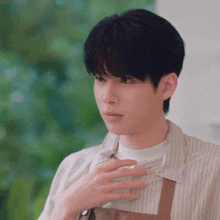 a young man wearing a striped shirt and apron is looking at something