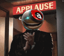 a man with a ball on his head applauds in front of an applause sign