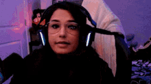 a woman wearing headphones and glasses is sitting in front of a computer .