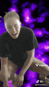 a man with a shaved head is kneeling down with a purple background .