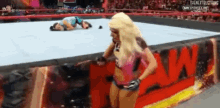 a woman is standing in a wrestling ring with the word raw in the background .