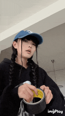 a girl wearing a blue hat is holding a roll of tape