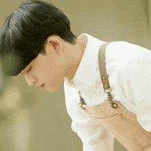 a man wearing an apron and a white shirt looks down at something