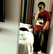 a man taking a selfie in front of a mirror wearing a red shirt that says ' almost dead ' on it