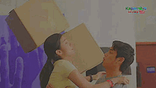 a man and a woman are fighting with a cardboard box on their heads .