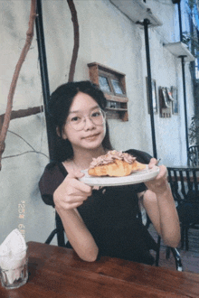 a girl sitting at a table holding a plate with a croissant on it with a date stamp of 25th of august