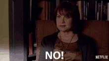 a woman is sitting in a chair with the word no on her face