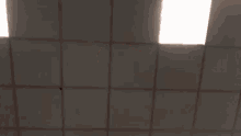 a man is making a funny face while standing in front of a ceiling .