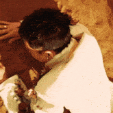 a man in a white shirt is laying on a brown surface