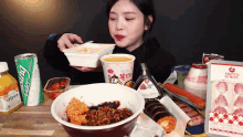 a woman is sitting at a table eating food and drinks including a can of ginger ale