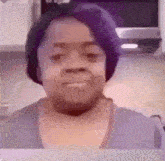 a woman with purple hair is smiling in a kitchen .