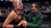 a woman in a green jacket is talking to another woman on a wrestling show .