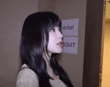 a woman is standing in front of a sign that says artist mgmt