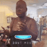 a woman is standing in a room with a blue button that says do n't move on it .