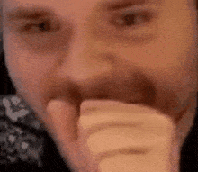 a man with a beard is covering his mouth with his hand and looking at the camera .