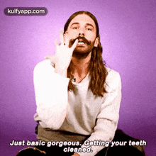 a man with long hair and a mustache is making a funny face while cleaning his teeth .