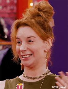 a woman with red hair wearing a necklace and earrings with the letter t on it