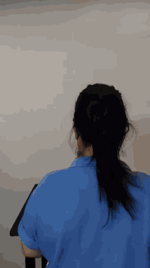 a woman in a blue shirt is sitting at a table