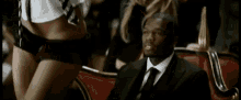 a man in a suit and tie is sitting next to a woman in lingerie