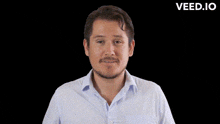 a man in a white shirt is standing in front of a black background with the word veed.io on the bottom